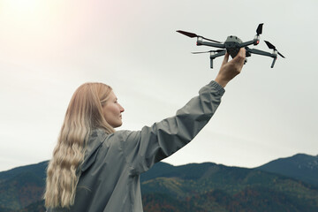 Young woman with modern drone in mountains