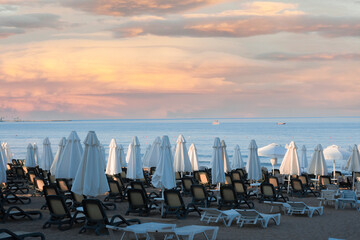 Obraz premium Beach views, Sun loungers, umbrellas, flags and small wavy coastline in Antalya Side. Selective Focus.