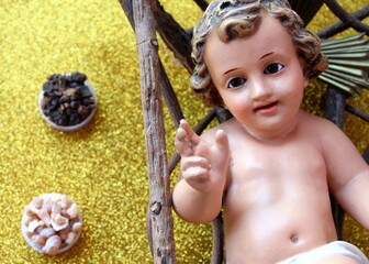 Christmas composition: frankincense and myrrh on a gold background next to the baby Jesus