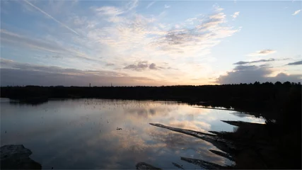 Fototapeten Sommer Creative background. Beautiful, atmospheric sunset in the sky. Orange, yellow rays of the setting sun against a blue sky with some white and dark clouds. High quality photo. High quality photo  © Bjorn B