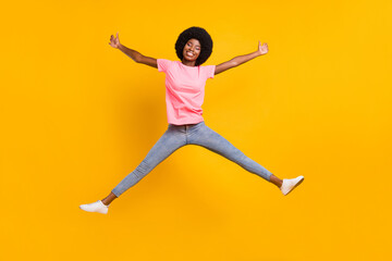 Full body photo of crazy millennial lady jump wear pink t-shirt jeans isolated on yellow color background