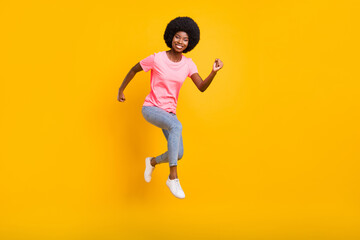 Full length photo of nice millennial lady jump run wear pink t-shirt jeans isolated on yellow color background