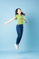 Portrait of beautiful young asian girl jumping up, isolated on blue background