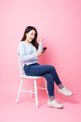 Fototapeta na wymiar portrait of beautiful asian girl sitting in chair, isolated on pink background