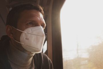 Man in protective mask N-95 in train. Tourist looking in window inside of railway wagon. Travel in...