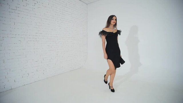 The woman in the black dress. Woman in black poses for the photographer in the studio. 