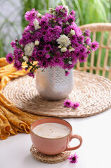 Cup of aromatic coffee and beautiful flowers on white table
