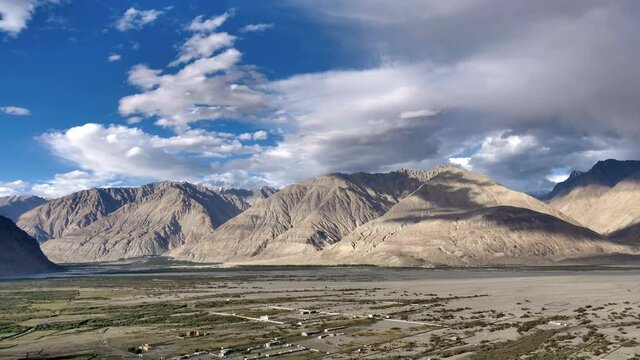 Time lapse of blue sky and  white clouds passing and creating pattern of shadows over the barren mountains and in the valley, Nubra Valley, Ladakh, Himalyas 