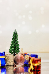 Merry Christmas, Happy New Year and Boxing day concept. Present boxes, world gloge crystal glass, pine tree and house models on light brown background.