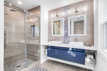 A modern bathroom with a blue cabinet, tile and stone back splash, and marble tiling the floor /...