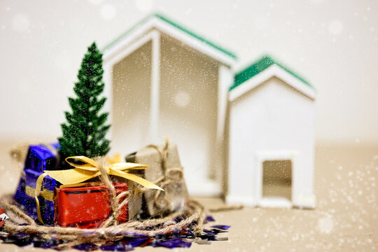 Merry Christmas, Happy New Year and Boxing day concept. Present boxes, world gloge crystal glass, pine tree and house models on light brown background.