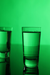 Vodka on table against green background, space for text