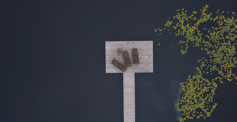 Two sunbeds on the wooden pier by the river with dry reeds next to it