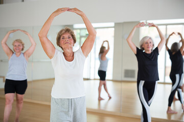 Fototapeta na wymiar Group of three mature women performing ballet dance in exercise room.