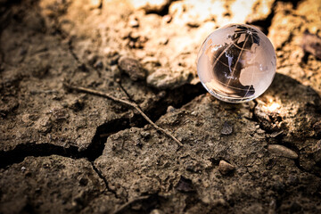 Climate change or global warming concept. World globe crystal glass on drought land.
