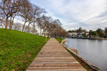 Wooden path in a modern city park during sunny fall season day. Located in Granville Island, Vancouver, British Columbia, Canada.