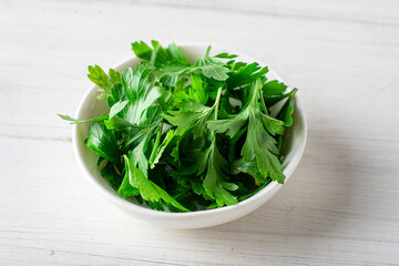 Fresh parsley on a plate on a white wooden background. Cooking ingredient.