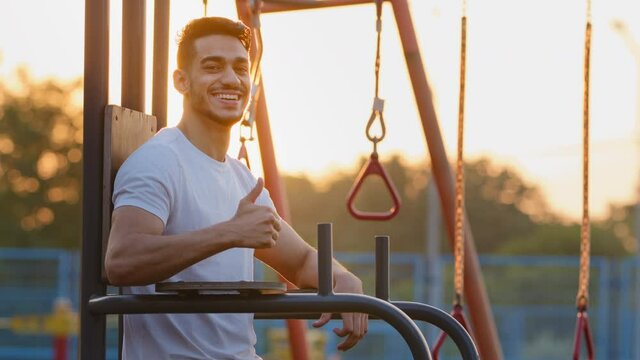 Happy attractive millennial Middle Eastern Arab athletic guy showing thump up gesture, satisfied good job, successful workout results. Young sporty Indian man student advertises effective equipment