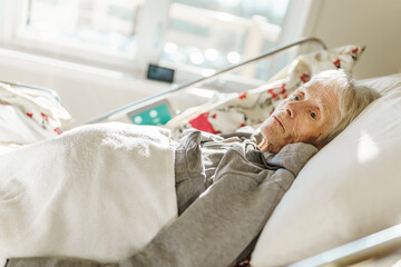 Sick, elderly senior woman in a hospital bed