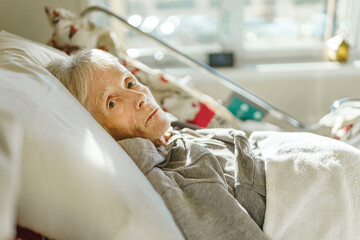 Sick, elderly senior woman in a hospital bed - obrazy, fototapety, plakaty