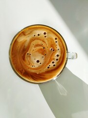 Top down view of cup of cappuccino in the sunlight on the white background
