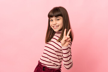 Little girl isolated on pink background smiling and showing victory sign