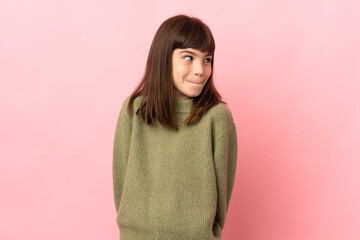 Fototapeta premium Little girl isolated on pink background having doubts while looking up
