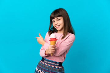Little girl with a cornet ice cream isolated on blue background pointing back