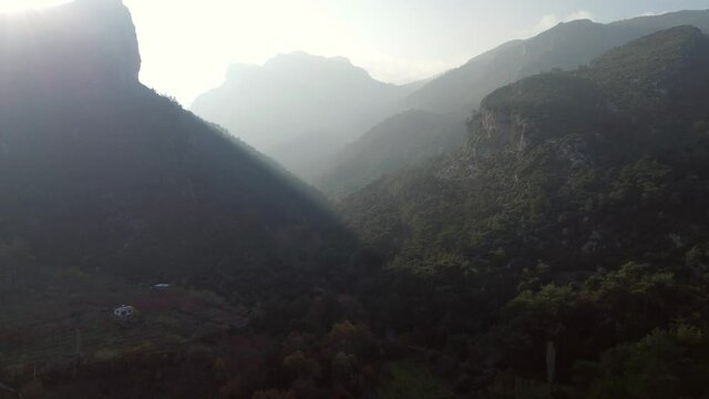 Aerial landscape footage of the hills and mountains with sun rays and some clouds.