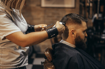 Young bearded man getting haircut by hairdresser