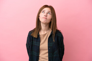 Young English woman isolated on pink background and looking up