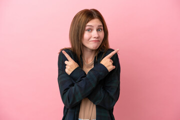 Young English woman isolated on pink background pointing to the laterals having doubts