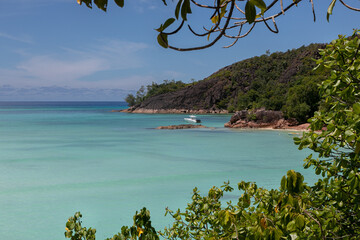 A view from high point to granite coast of a tropical island. Shore covered with jungle. A yacht is...