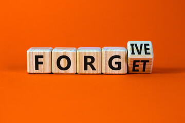 Forgive and forget symbol. Turned a wooden cube and changed the word forgive to forget. Beautiful orange background, copy space. Business, psychological forgive and forget concept.