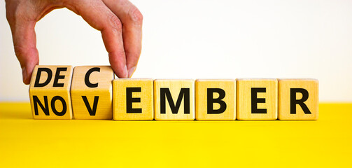 Symbol for the change from November to December, winter. Businessman turns wooden cubes and changes the word 'November' to 'December'. Beautiful white background, copy space. Happy December concept.