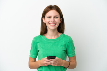 Fototapeta premium Young English woman isolated on white background looking at the camera and smiling while using the mobile