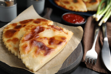 Delicious fried chebureki served on black table, closeup
