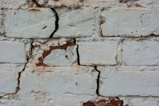 View of white brick shabby wall with cracks. Copyspace. Closeup