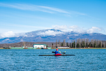 a man rower floats on a kayak rowing oars. background mountain landscape