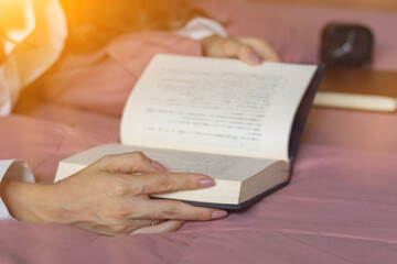 A girl is reading bible in bed to study and learn God's teachings before she goes to bed and understand for proper prayer and blessing from God with belief and power of faith in God.