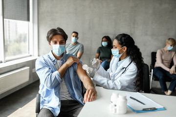Millennial man getting intramuscular shot in shoulder, vaccination while pandemic