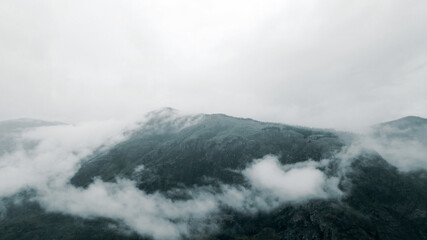 Obraz premium Flying in the clouds to the mountain during light rain