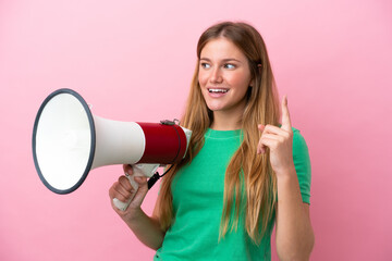 Young blonde woman isolated on pink background holding a megaphone and intending to realizes the...