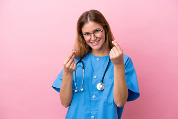 Young surgeon doctor woman isolated on pink background making money gesture