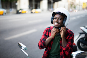 African man with scooter in the city. Young man riding a scooter..