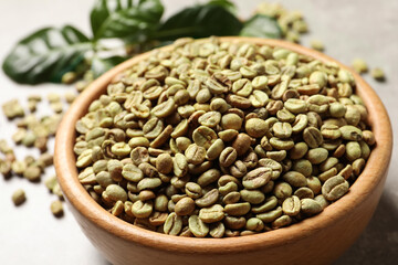 Green coffee beans in wooden bowl on table, closeup