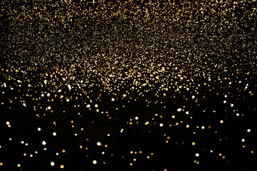 Black festive background. Abstract scattering of gold sparkles on black. Holiday backdrop, selective focus