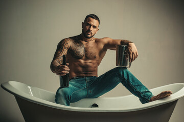 Sexy seductive muscular man sit on bathtub, men holiday with champagne. Celebrating christmas or birthday. Private sex party. - obrazy, fototapety, plakaty