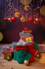 Christmas socks, gifts and balls under red and golden Christmas decorations and glowing lights.
