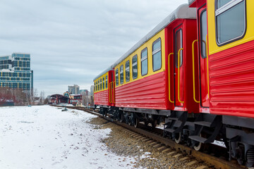 passenger train on a narrow gauge railway against the background of the city